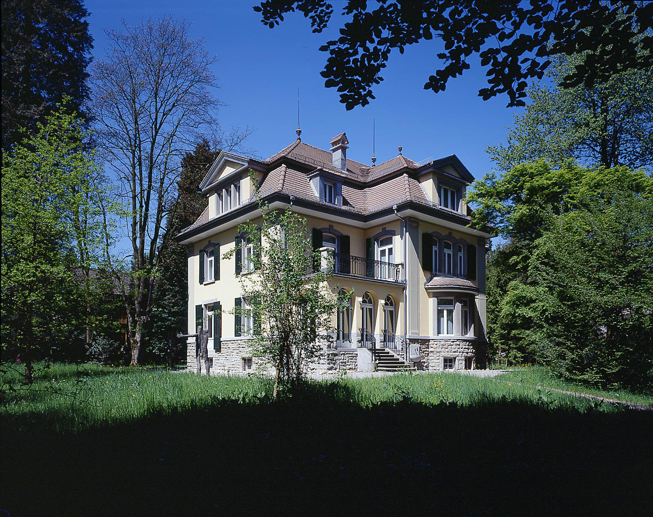 Ein grosses Haus in einem frühlingshaften Park. 