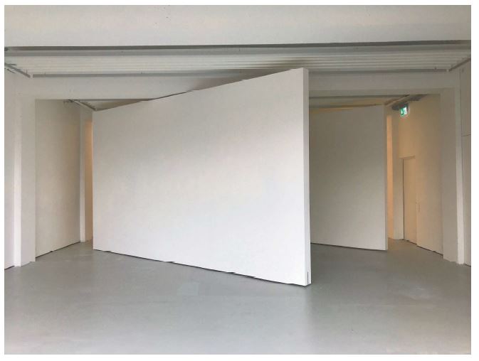 Eine weisse Wand steht diagonal in einem white cube Ausstellungsraum