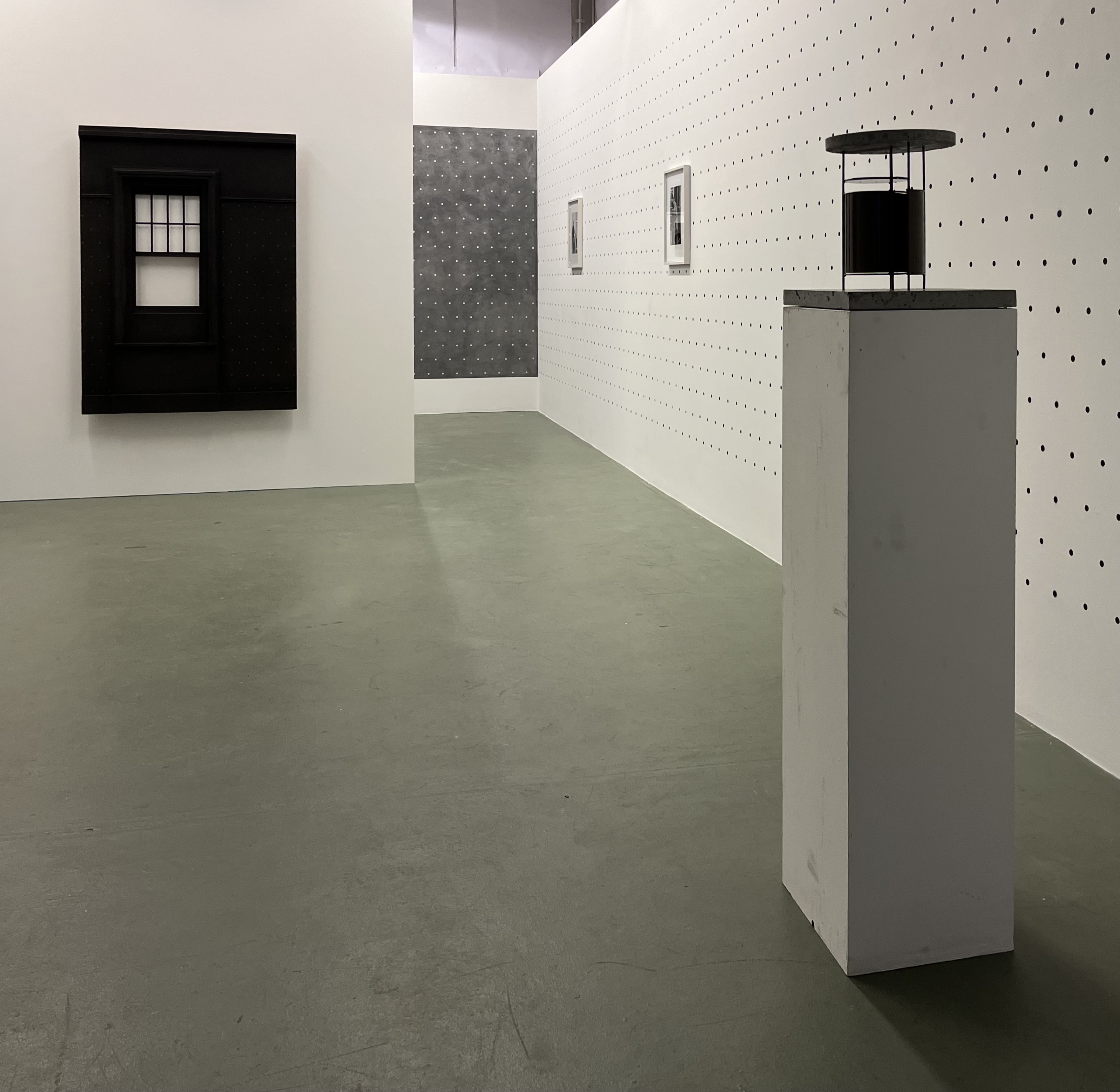 Bernard Voïta - Insomnie Géométrique bei Edizioni Galleria Periferia. Links eine Wandskukptur einer schwarzen Fassade, rechts ein Sockel mit einer kleinen schwarzen Skulptur darauf