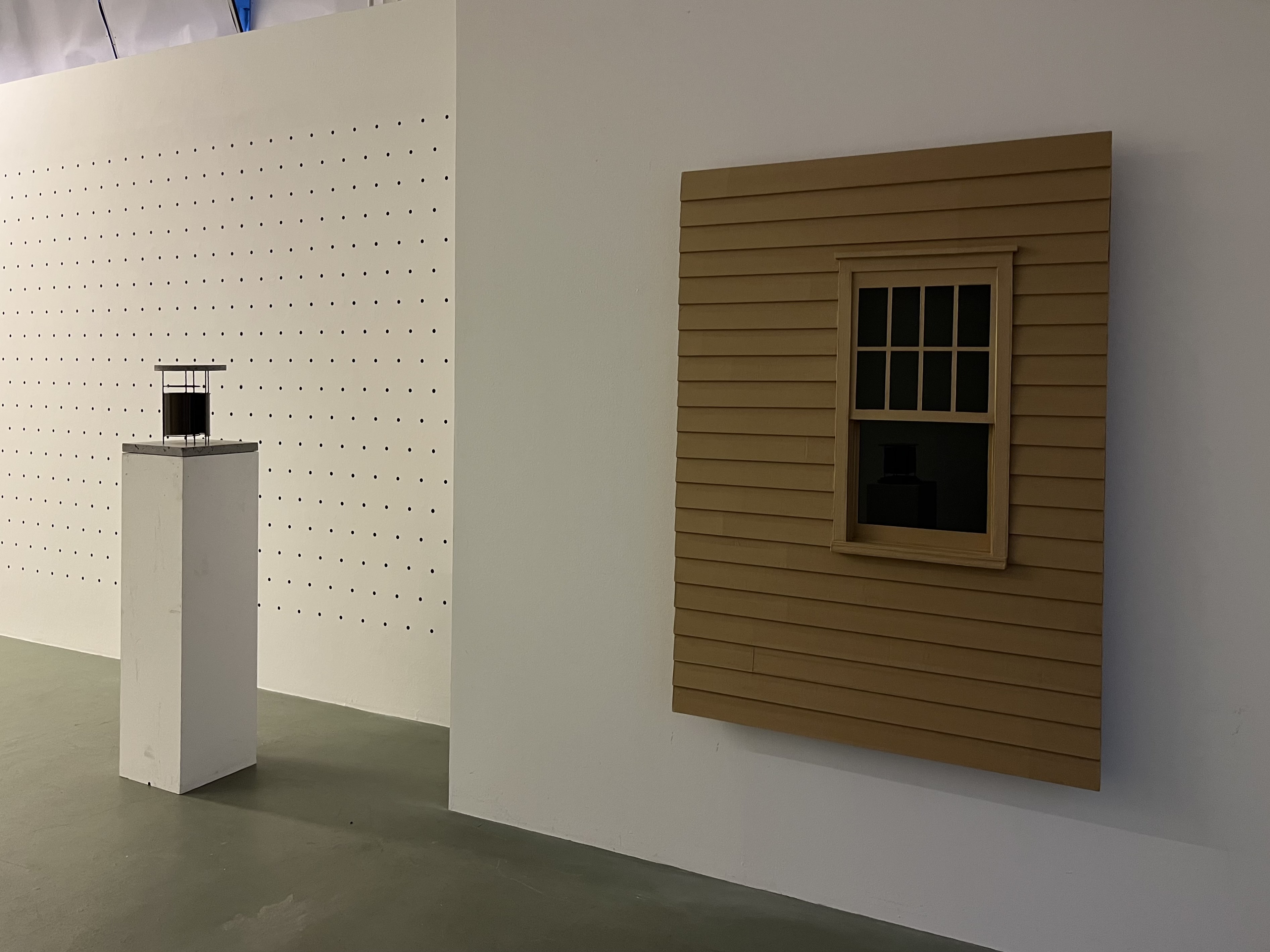 Bernard Voïta - Insomnie Géométrique bei Edizioni Galleria Periferia, Rechts: Wandskulptur einer Fassade mit Fenster, links ein Sockel mit einer kleinen schwarzen Skulptur darauf