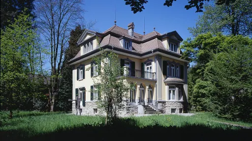 Ein grosses Haus in einem frühlingshaften Park. 