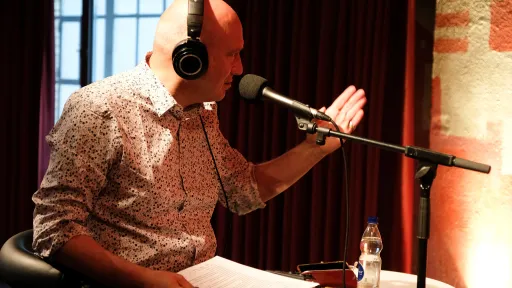 Ein Mann mit Kopfhörern gestikuliert und spricht in ein Mikrofon