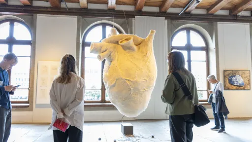 Zwei Personen schauen sich eine Skulptur eines riesigen Herzens aus Filz an.
